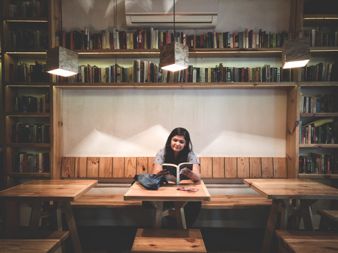 A young woman reading a book in a warmly lit library in India
